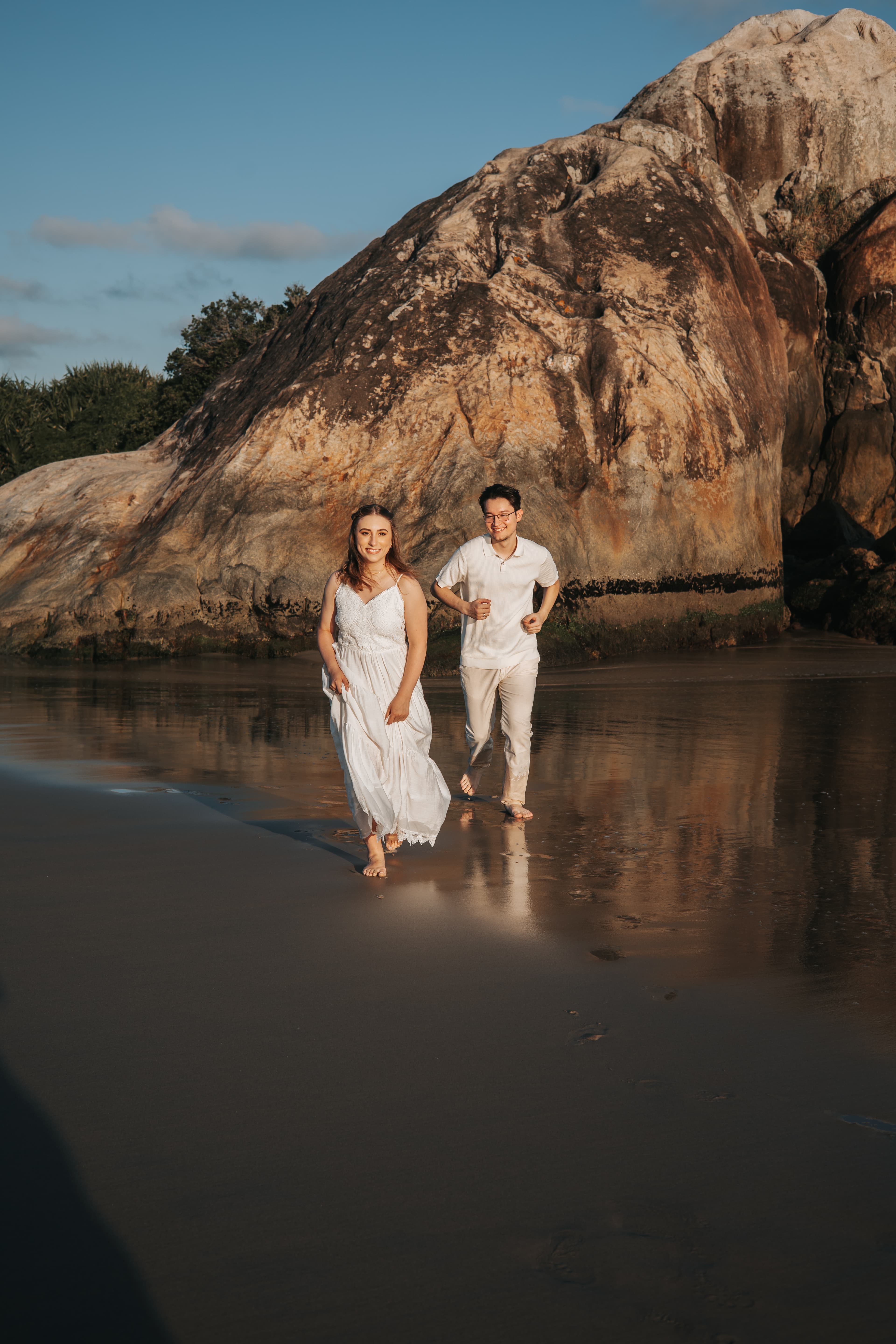 Rafaela e Mateus na praia em frente as pedras